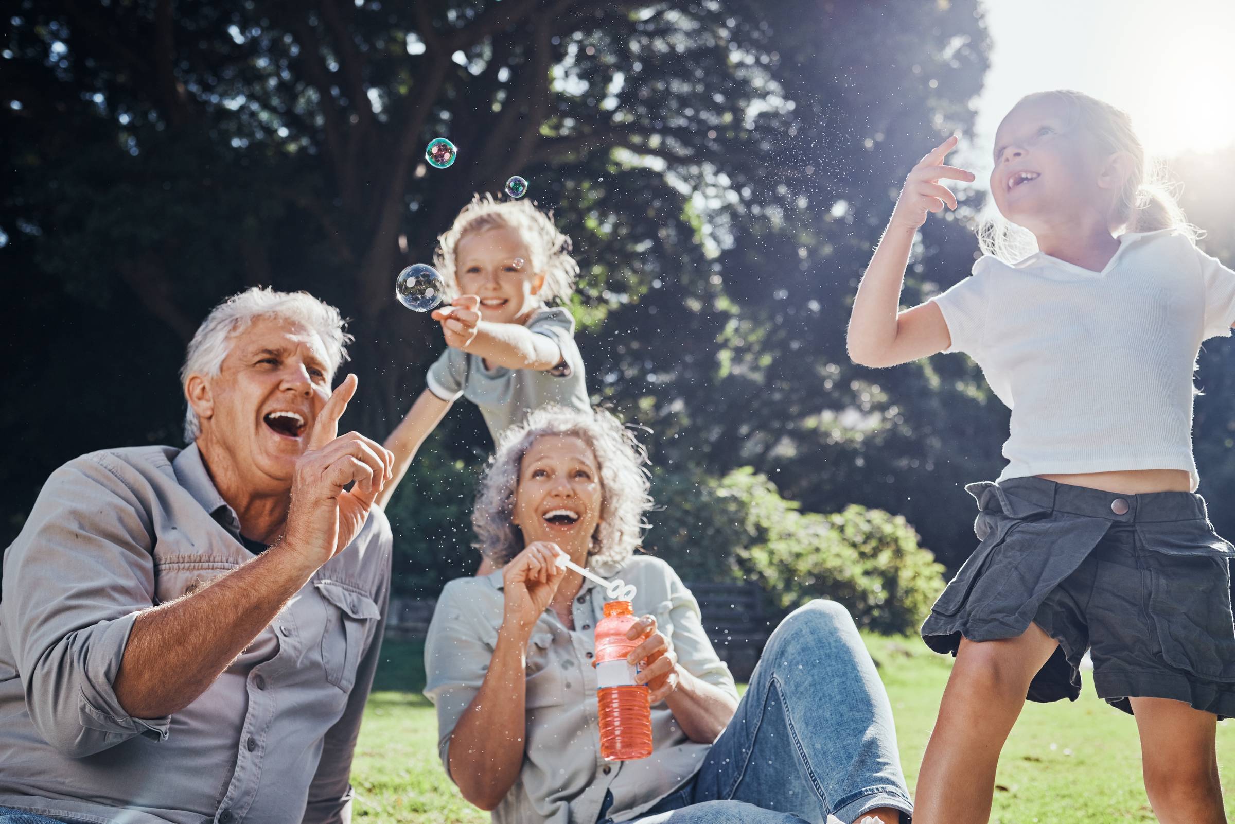 Royce Townhomes Two older adults and two children laugh and play with bubbles together outdoors on a sunny day.