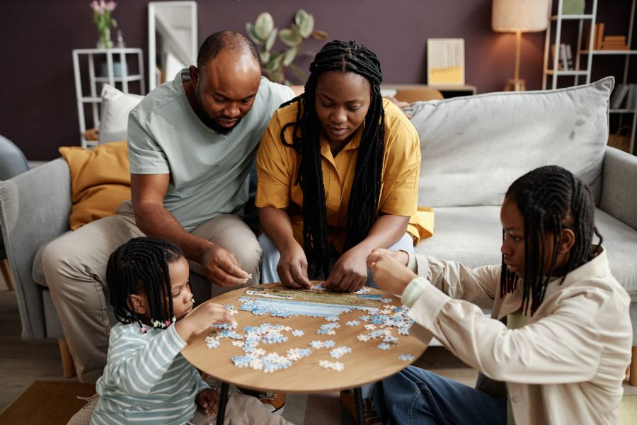 Royce Townhomes A family of four sits around a table, assembling a jigsaw puzzle together in a cozy living room.