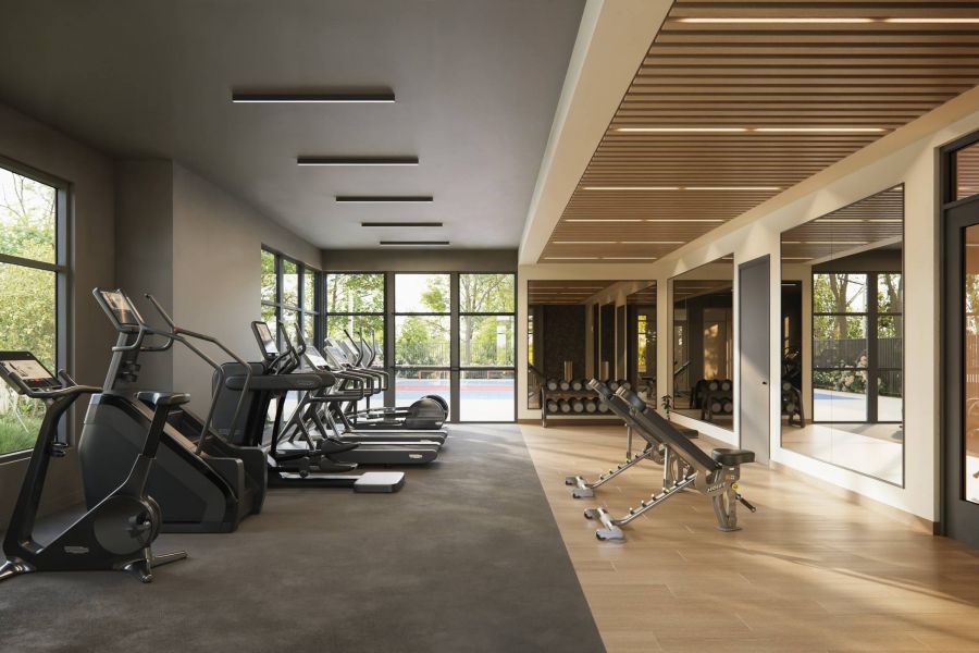 Royce Townhomes Modern gym with treadmills, ellipticals, benches, mirrors, dumbbells, and large windows overlooking greenery.